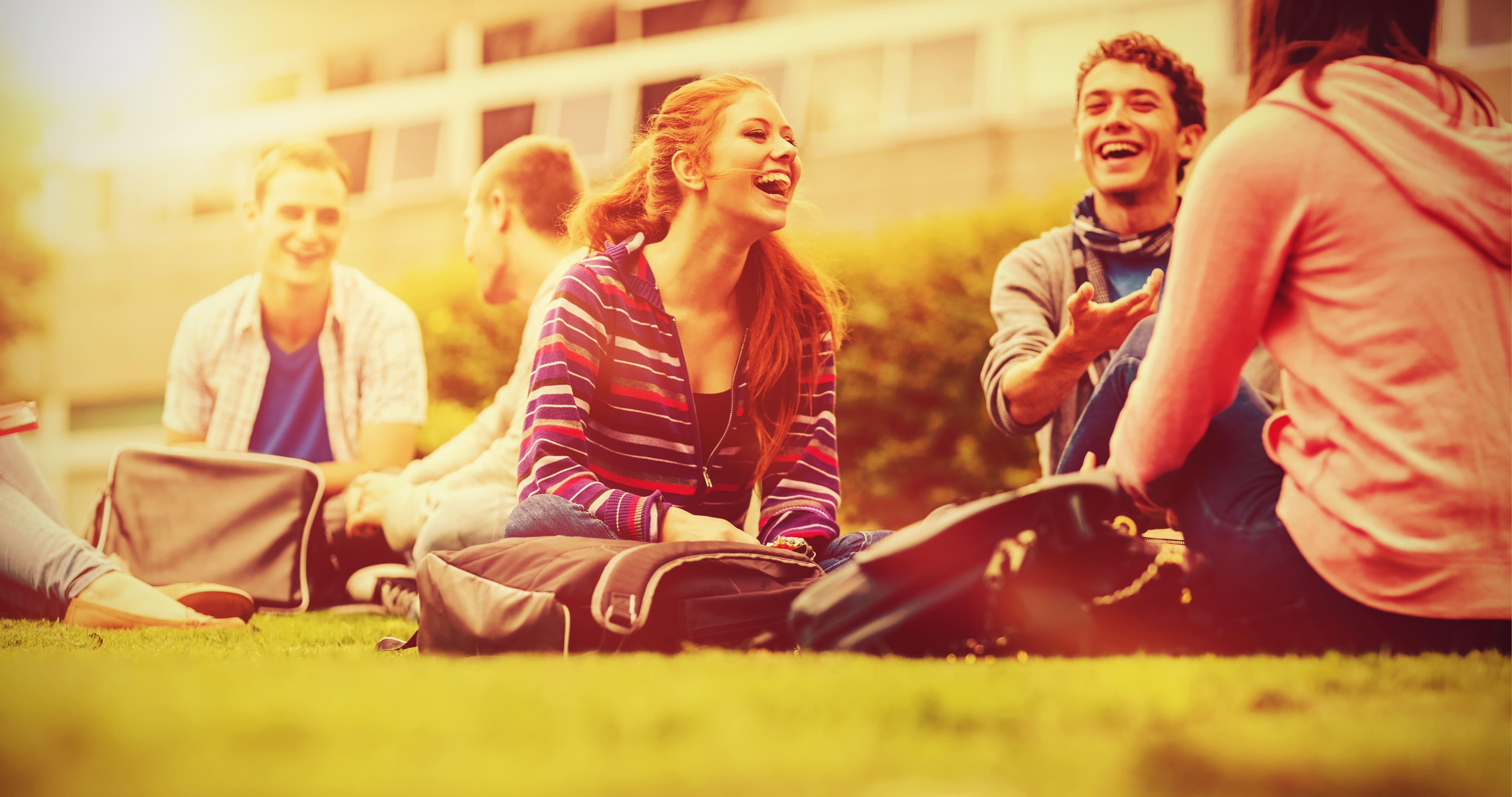 Students sitting outside relaxing and laughing